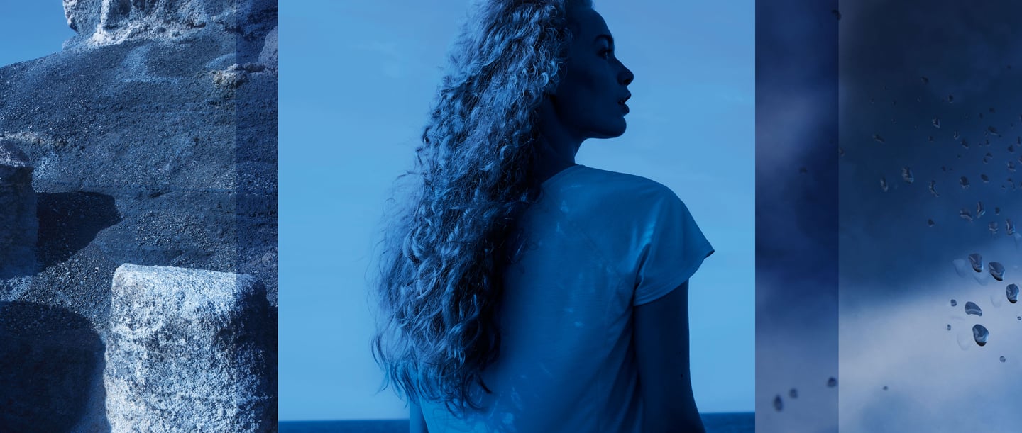 The picture shows a woman from behind, surrounded by a bluish tone that creates a cool atmosphere. She is wearing clothing from the CALIDA DEEPSLEEPWEAR COOLING collection, which was specially developed for heat. The woman's relaxed pose conveys comfort and calm, while representing the perfect clothing for hot nights.