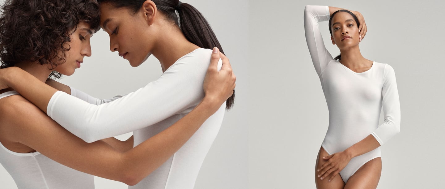 Two women in plain white bodysuits. The left half of the picture shows the two women in an intimate embrace, while the right half shows one of the women posing confidently with one hand behind her head.