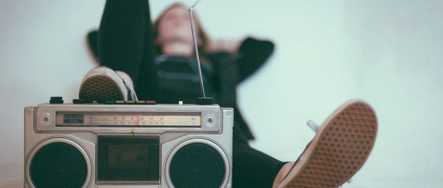 Person entspannt sich mit einem Retro-Radiorecorder und ausgestreckten Beinen.