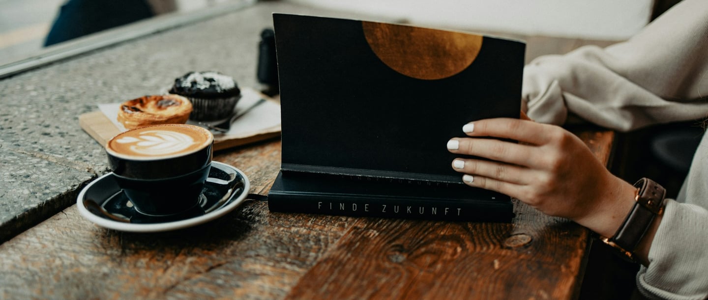 Digital detox in a café - a person with a book and coffee, without digital distractions.