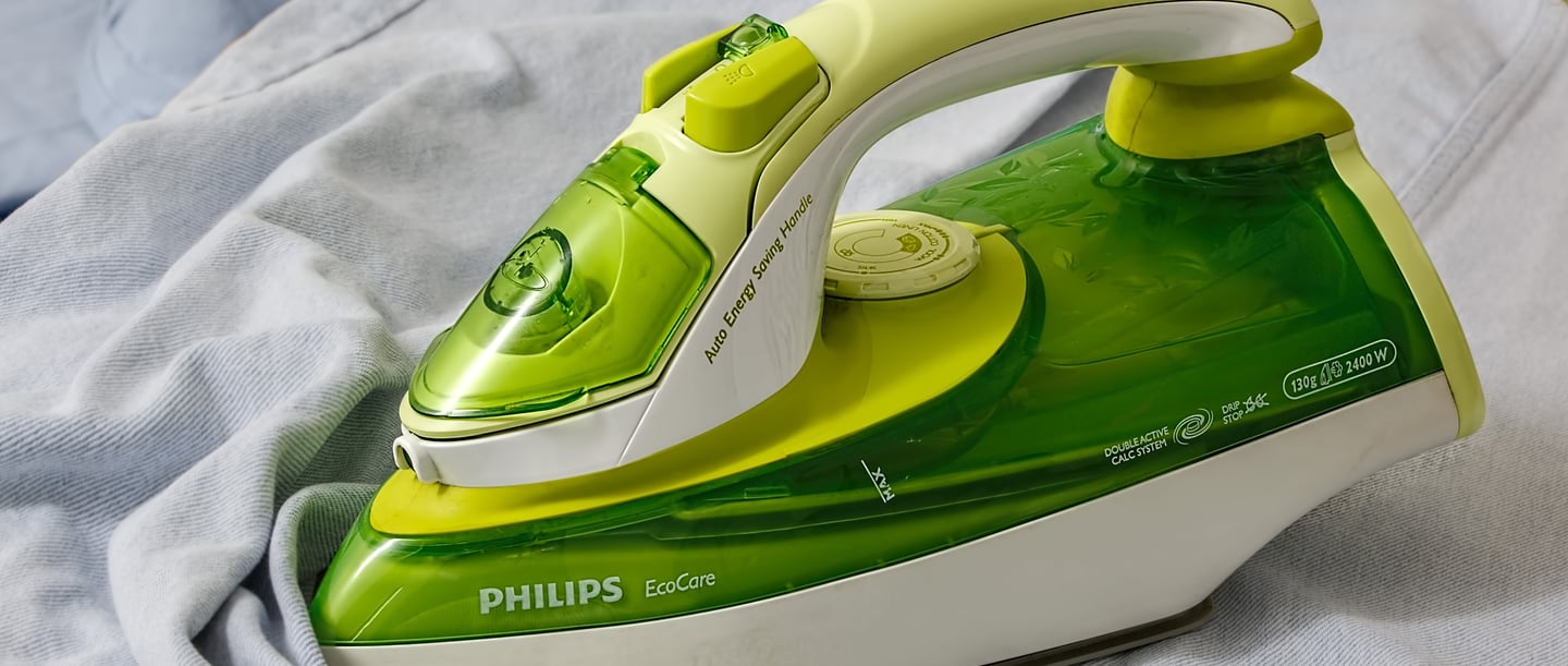 A green Philips iron on a garment - tips and techniques for correct ironing made easy.