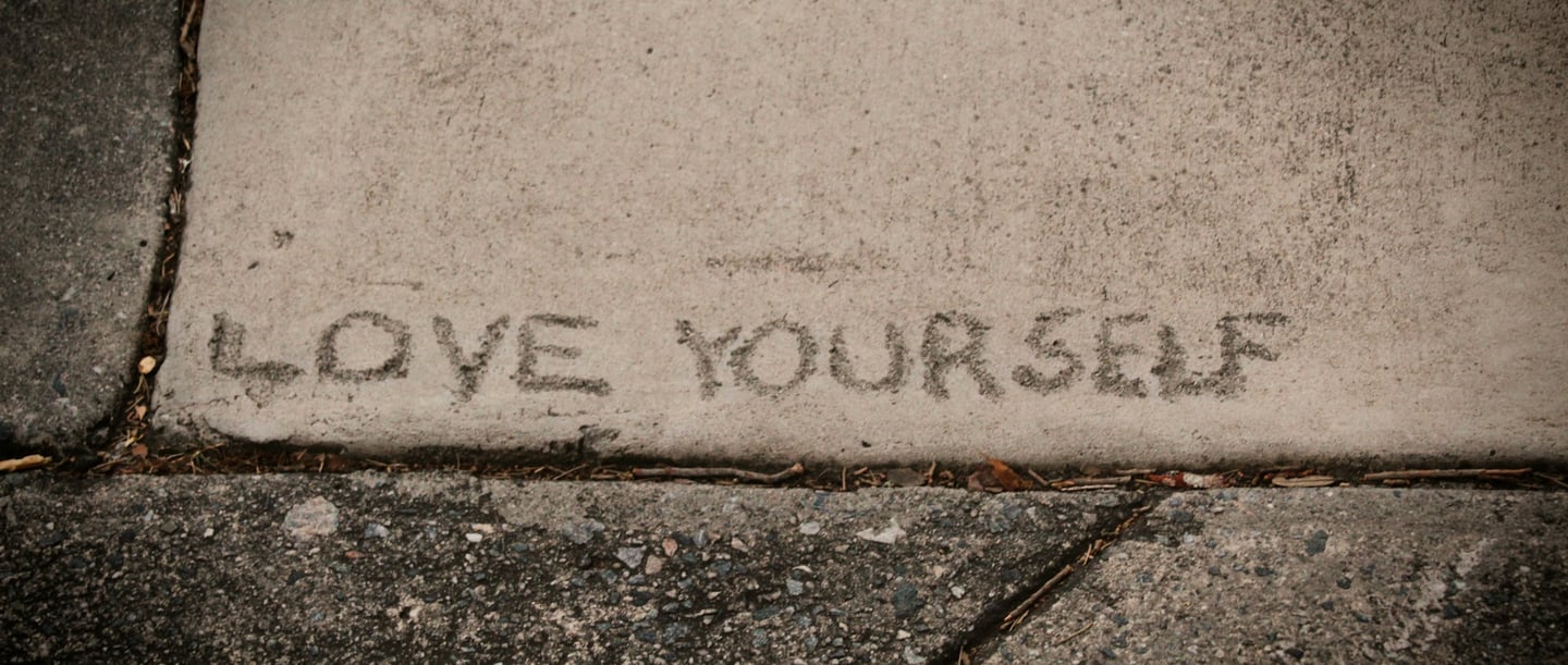 The words ‘LOVE YOURSELF’ engraved in the concrete - learn to love yourself and value yourself.