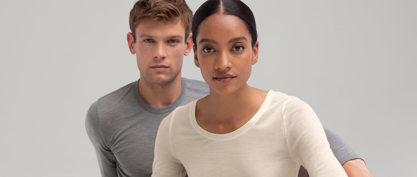 Mann und Frau tragen wärmende Wäsche von CALIDA aus der Serie True Confidence. Der Mann trägt ein graues Langarm-Shirt und die Frau ein weisses Langarm-Shirt.