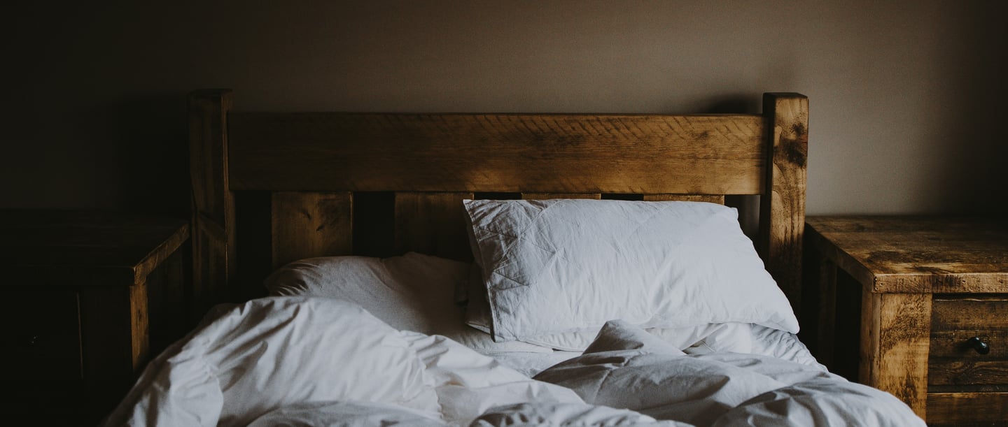 Ein Bett auf dem ein weisses Kissen und ein weisse Decke liegt.