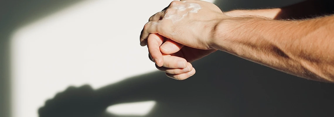 Mani di un uomo con crema bianca sul palmo superiore