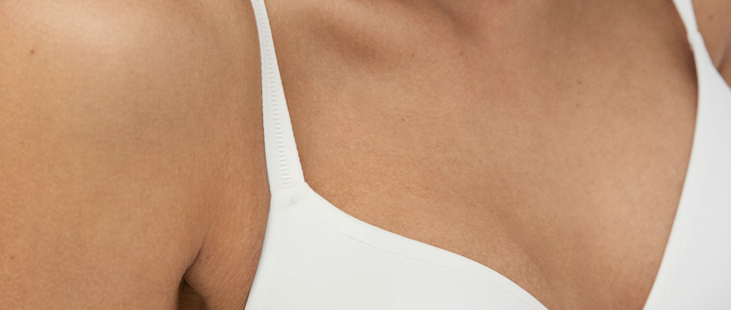 Close-up of a woman wearing a white bra, with the bra straps well positioned to avoid the problem of bra strap slippage.