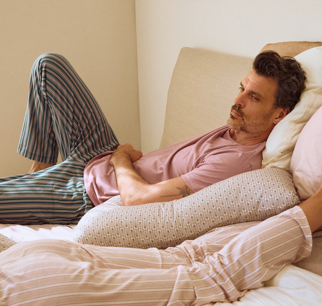 Ein männliches Model liegt auf einem Bett und trägt einen Pyjama der Mix & Match Reihe