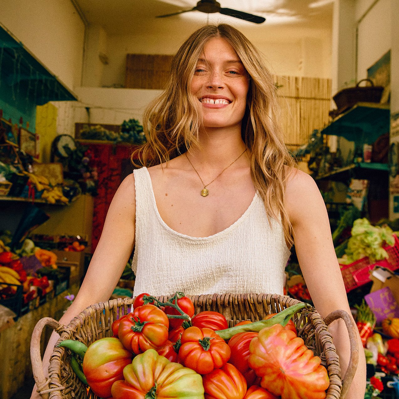 A woman holding a basket full of tomatos.