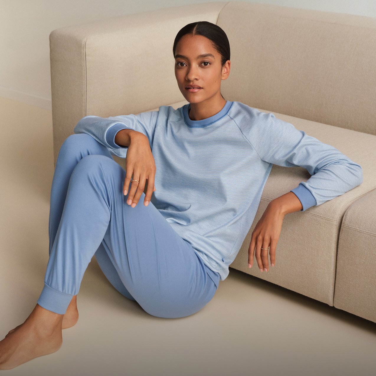 The model is wearing light blue striped cuffed pyjamas from the Midnight Stripes range by CALIDA.