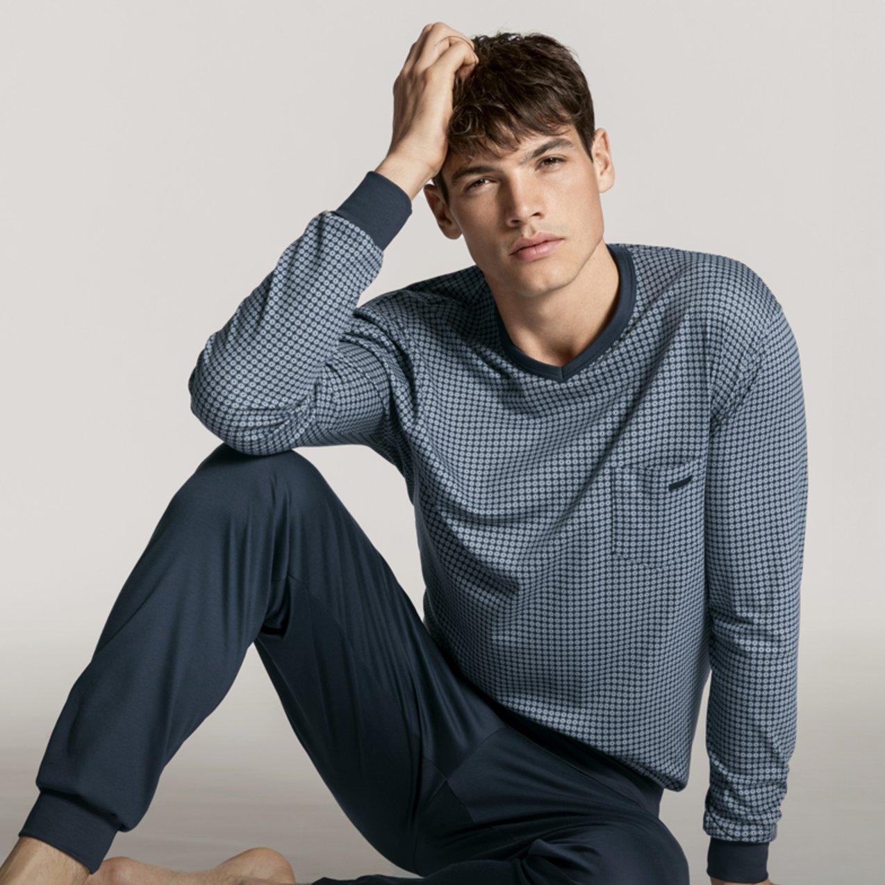 The gentleman is wearing blue pajamas with cuffs.