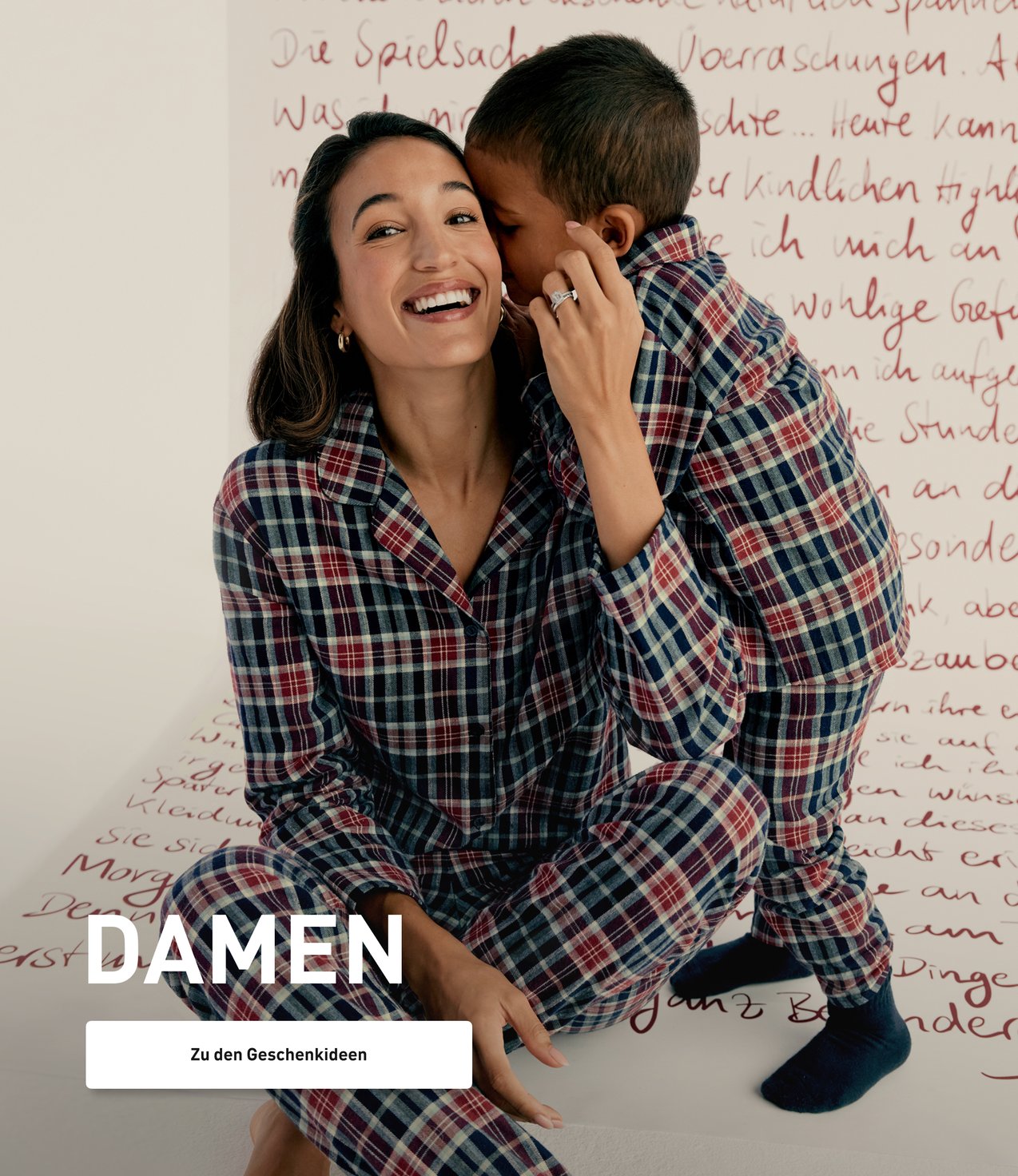 Model trägt einen karierten Flanell-Schlafanzug im Partnerlook mit Kind und präsentiert winterliche Nachtwäsche für die ganze Familie.