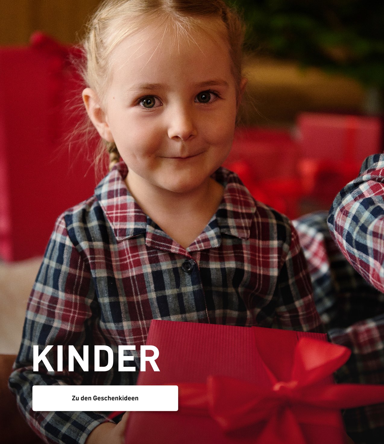 Kinder in Weihnachtspyjamas mit Geschenken in der Hand.
