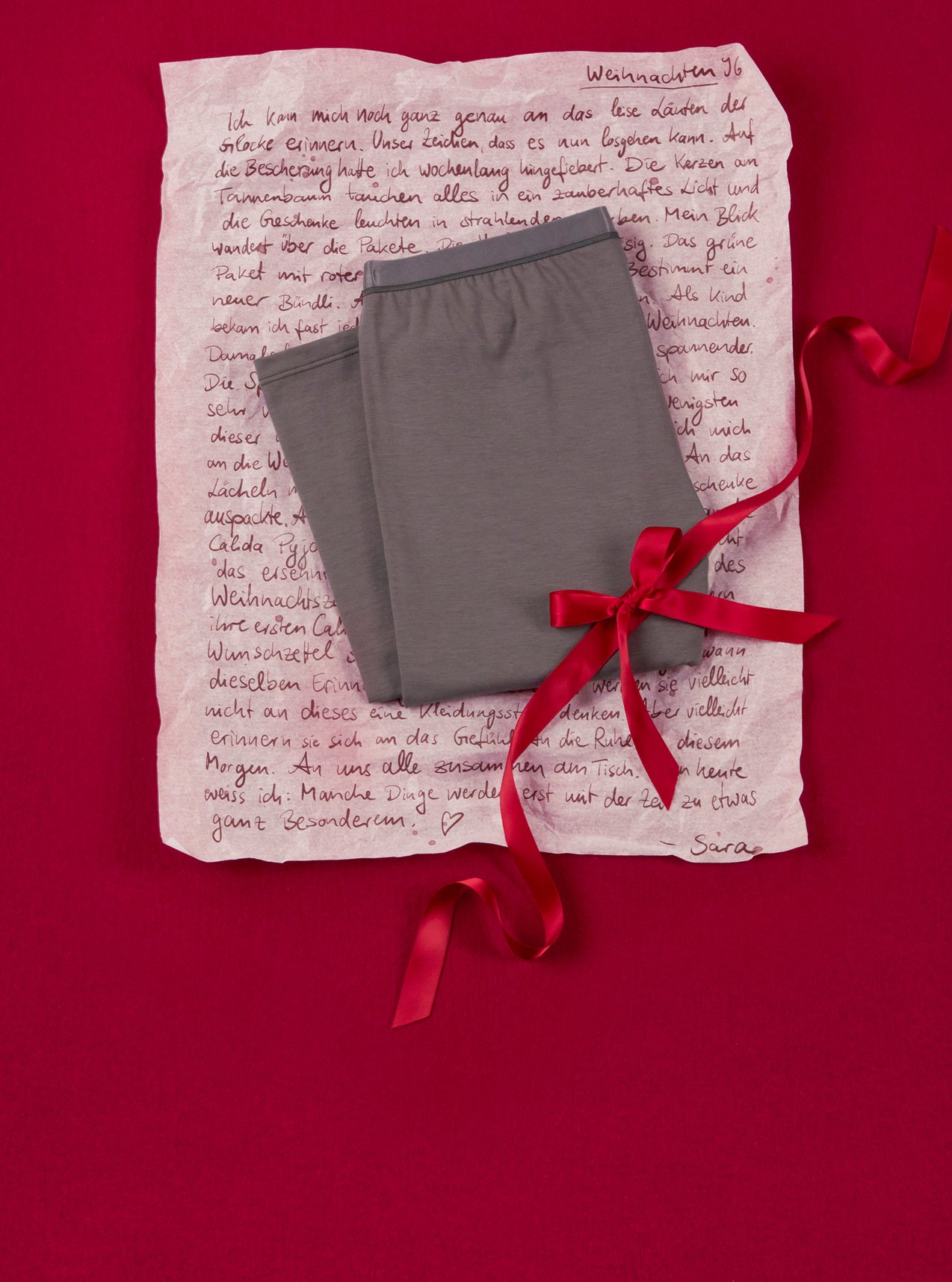 Trendy homewear pants in grey, arranged with a gift ribbon and personal touch on a festive background.