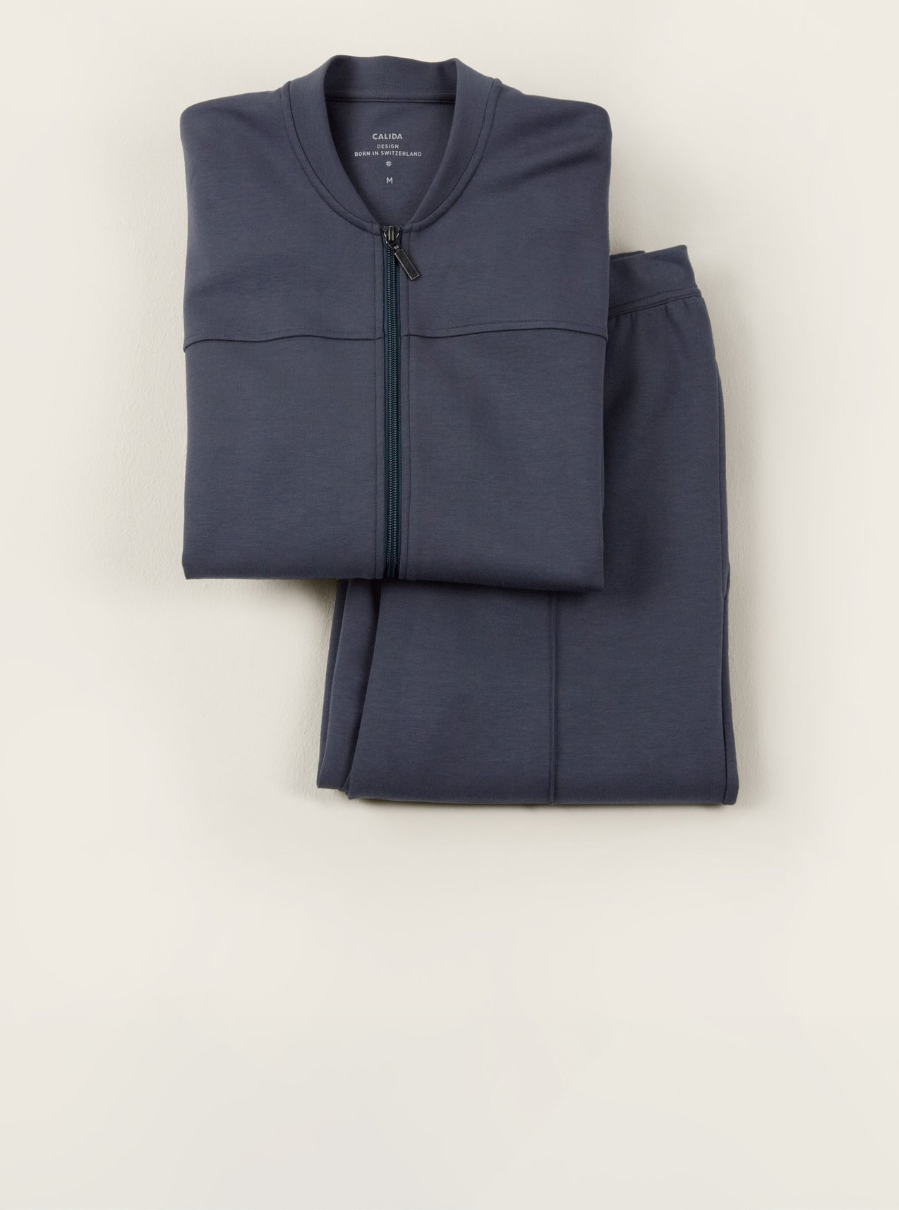 Comfortable homewear set in blue with zip-up jacket and matching pants, decoratively arranged as a gift idea.