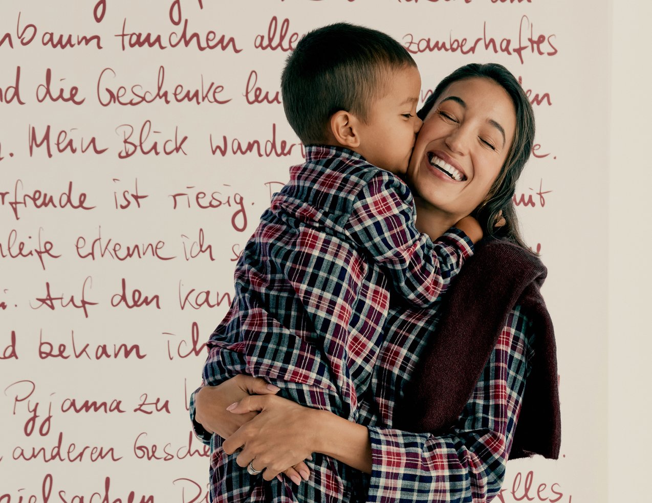Model wears a plaid flannel pajama set matching with child and presents winter nightwear for the whole family.