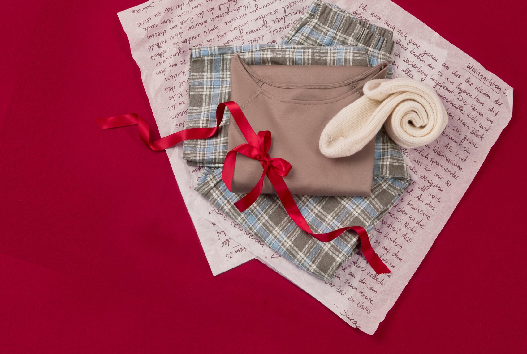 Cozy loungewear with plaid pants and cuddly socks, festively staged with ribbon.