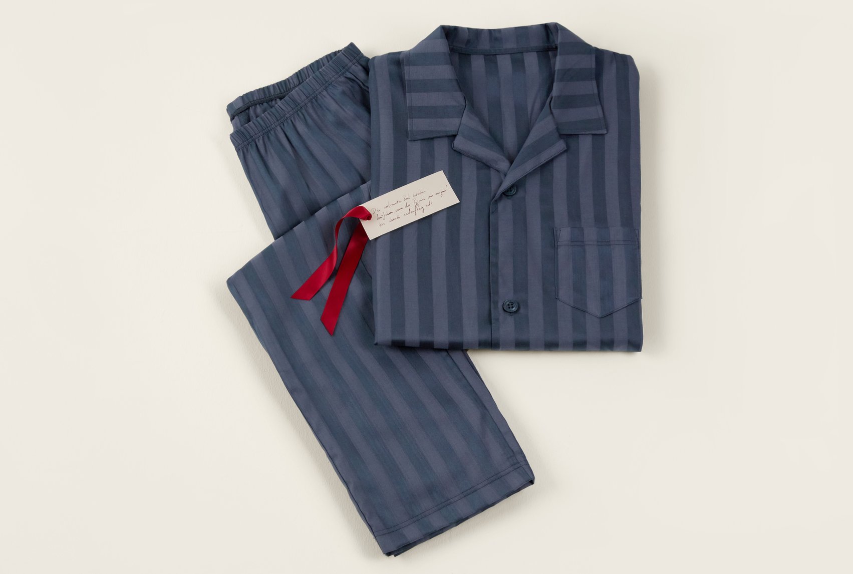 Striped pajamas with a shirt collar and matching pants, decoratively presented as a gift set.