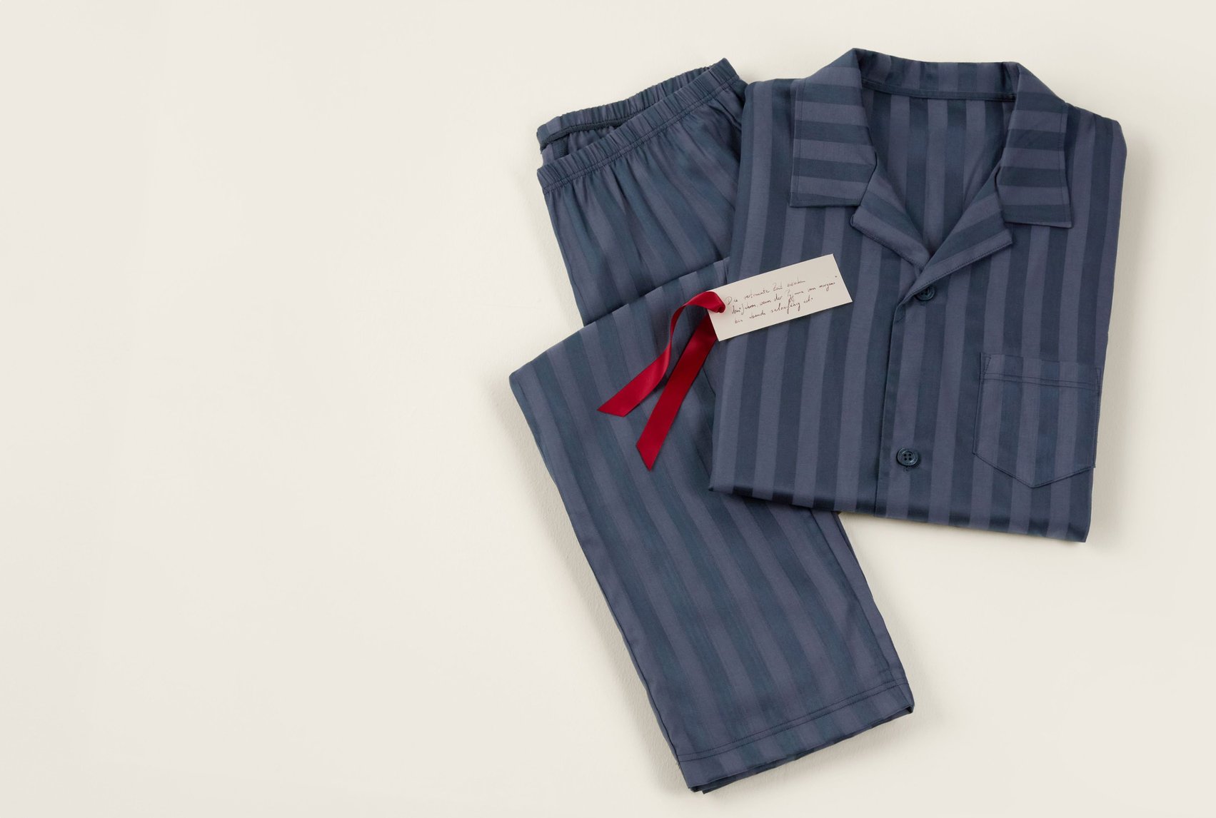 Striped pajamas with a shirt collar and matching pants, decoratively presented as a gift set.