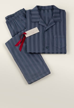 Striped men's pajamas in blue with a shirt collar and matching pants, festively arranged as a gift set.