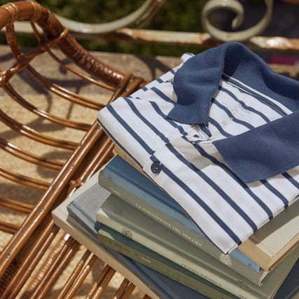 The image shows a blue and white striped nightshirt lying on a pile of books.