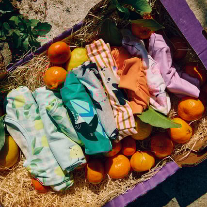 Kids pyjamas in a box of friuts.