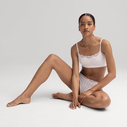 La modella indossa un bustier bianco e mutandine bianche del marchio CALIDA della serie Etude Toujours.