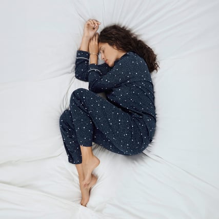 La modella indossa un pigiama blu scuro del marchio CALIDA della serie Sweet Dreams. 