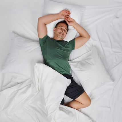 The model is wearing green pyjamas from the CALIDA brand, from the Deepsleepwear series. 