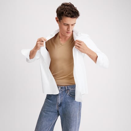 The model is wearing a beige shirt from the Natural Cooling range by CALIDA. 