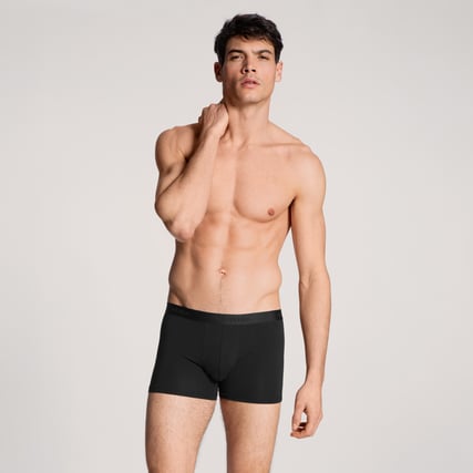 Das Model trägt eine blaue Boxer aus der Serie Natural Benefit und einen dunkelblauen Pullover aus der Serie Circular Lounge.  