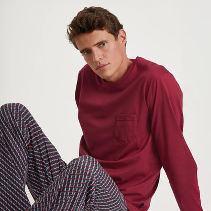 The model is wearing red pyjamas from the CALIDA Relax Imprint range. 