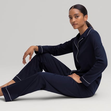 Das Model trägt einen dunkelblauen, durchgeknöpften Pyjama aus der Serie Night Lovers der Marke CALIDA.