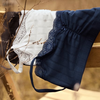 Das Bild zeigt drei Bustiers der Marke CALIDA aus der Serie Etude Toujours in den Farben, schwarz, weiss und blau. 