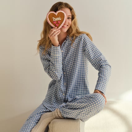 Das Model trägt einen durchgeknöpften, blau-karierten Pyjama aus der Serie Flannel Dreams der Marke CALIDA. 