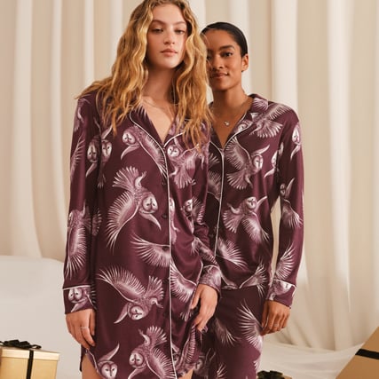 Ein Model trägt ein dunkelrot-bedrucktes Nachthemd und das andere Model einen duneklrot-bedruckten Pyjama aus der Serie Moonlight Dreams der Marke CALIDA. 