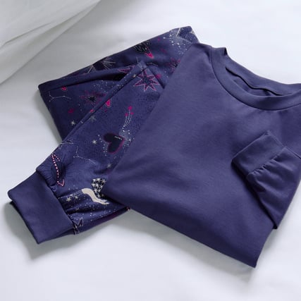 Das Bild zeigt ein duneklblaues Oberteil und eine dunkelblau-gemusterte Hose aus der Serie Mystic Night der Marke CALIDA. 