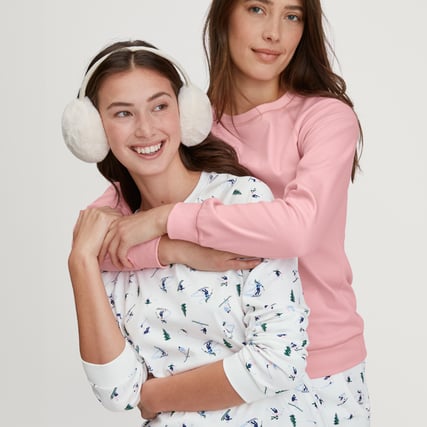 Das eine Model trägt einen rosernen Pyjama und das andere Model trägt einen weißen Pyjama mit kleinen Skimotiven aus der Serie Ski Resort der Marke CALIDA.