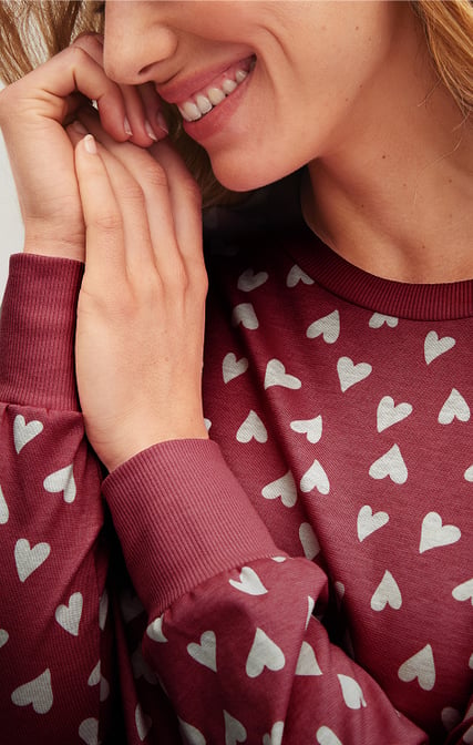 The lady is wearing a pair of Cotton Special pyjamas with cuffs and a heart design