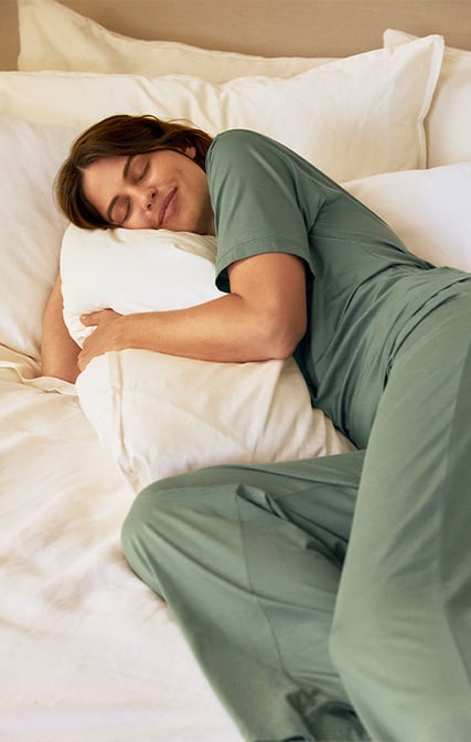 The lady is wearing a breathable pajama from the Deepsleepwear Balancing collection in green.