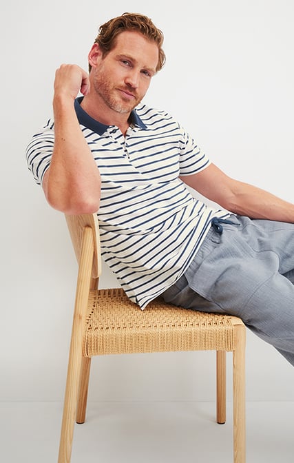 The man is wearing an RMX Lounge Journey polo shirt in the color Dark Denim, paired with RMX Sleep Journey pajama pants.