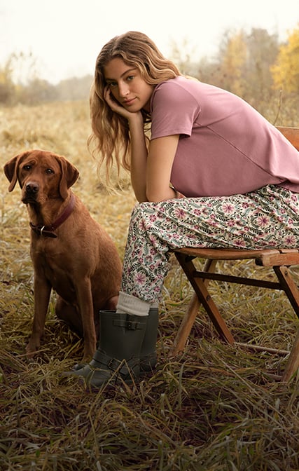 Das Model trägt ein rosanes T-Shirt und eine blumig-bedruckte Hose aus der Serie Favourites Botanic der Marke CALIDA.