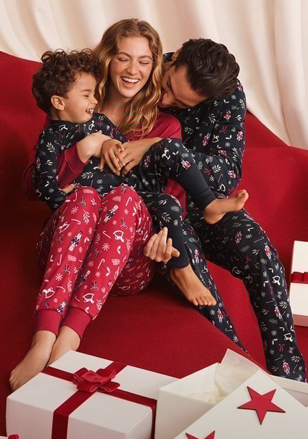 La photo montre une femme, un homme et un enfant portant le même pyjama.