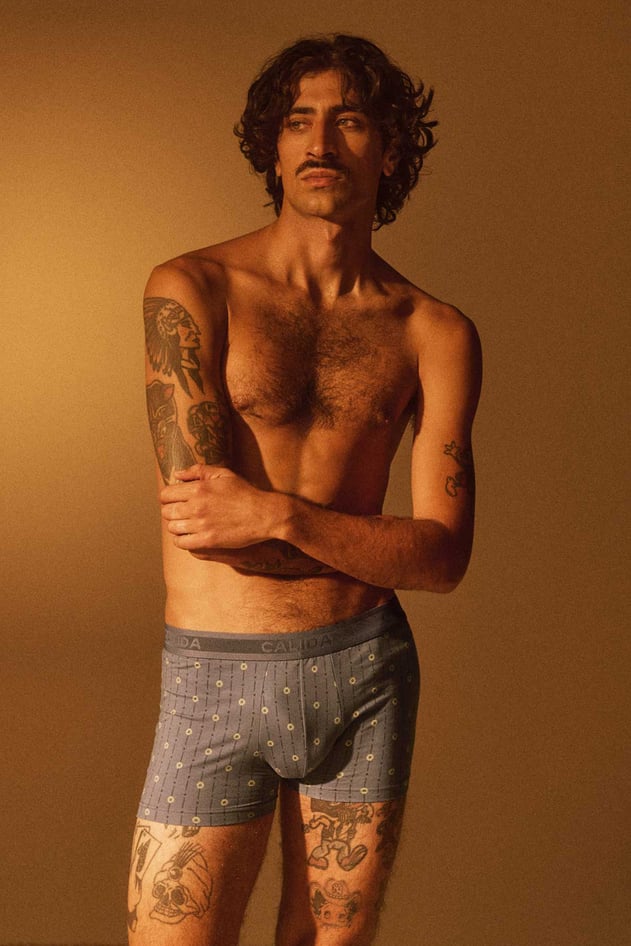 Boxer shorts with pattern: Person wears light blue boxer shorts with a small all-over pattern against a solid background.
