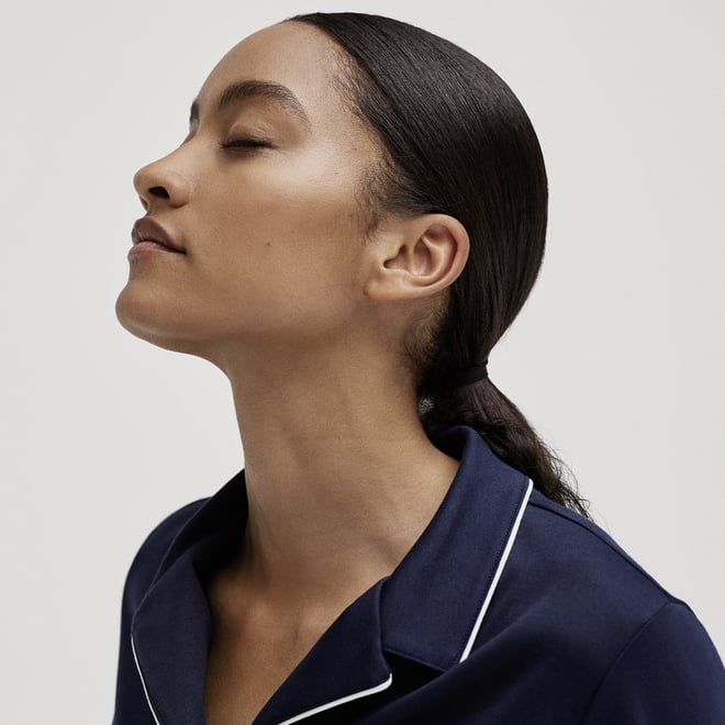 Woman in profile with closed eyes and dark blue CALIDA nightwear against a light background