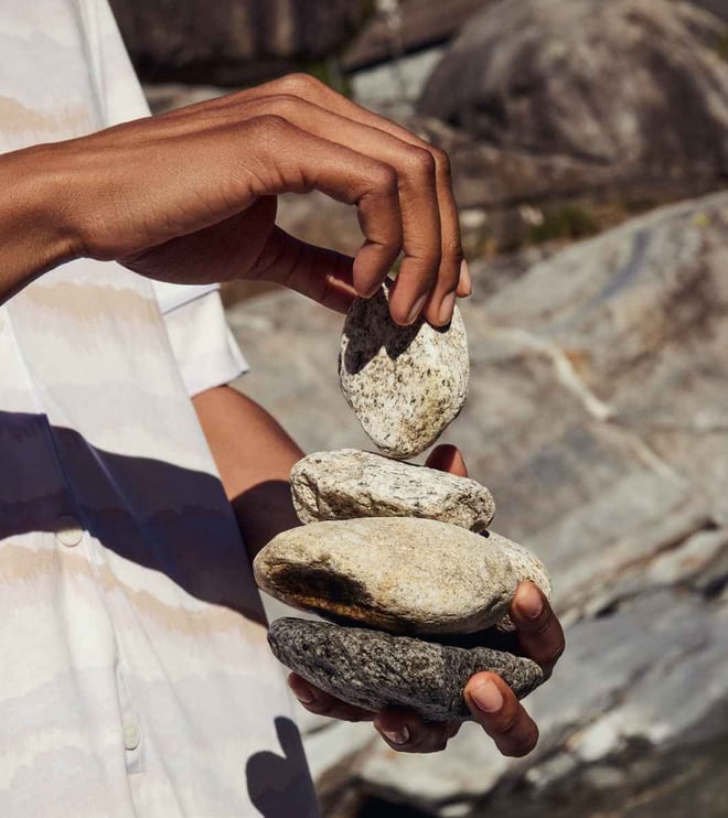 Hands of a person stacking smooth stones; calm scene focusing on balance and mindfulness