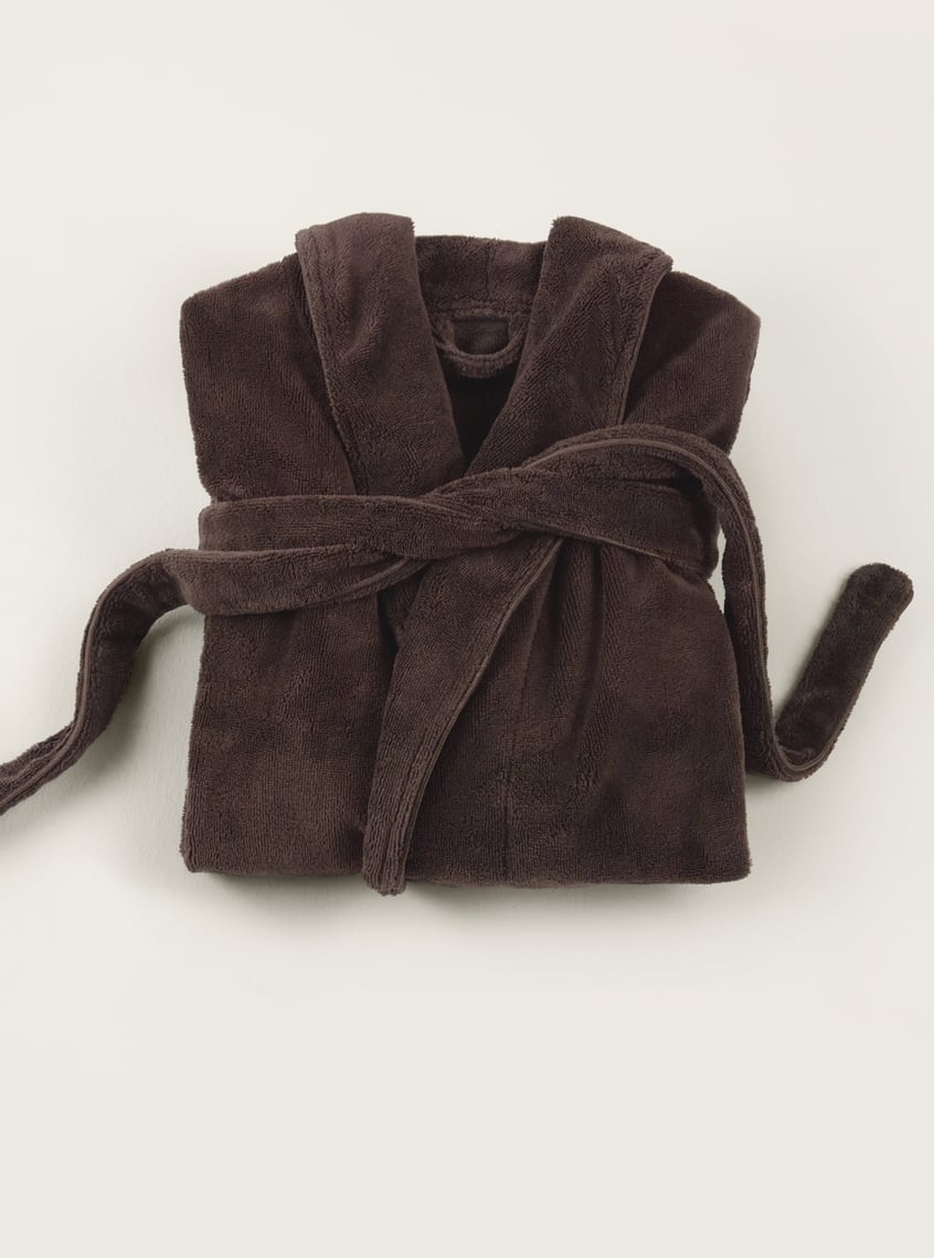 Soft bathrobe in dark brown, decoratively folded and arranged as a wellness gift idea.