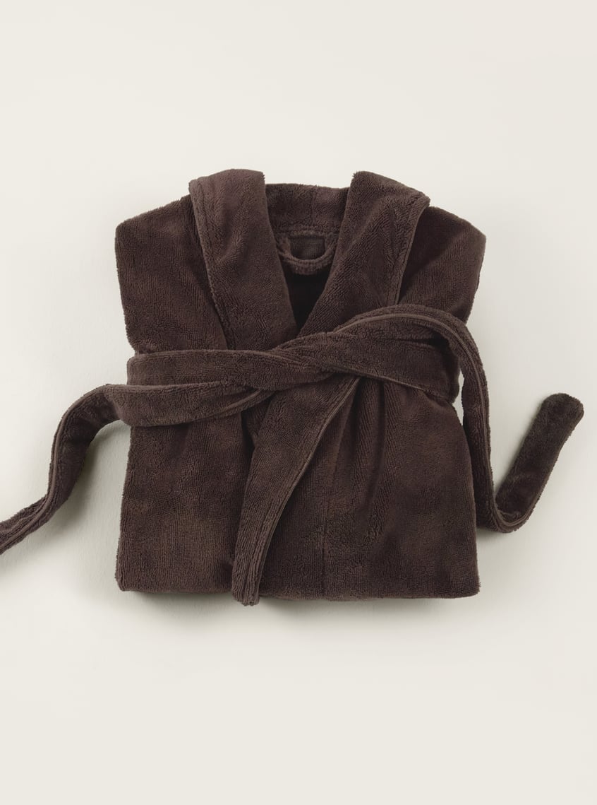 Soft bathrobe in dark brown, decoratively folded and arranged as a wellness gift idea.