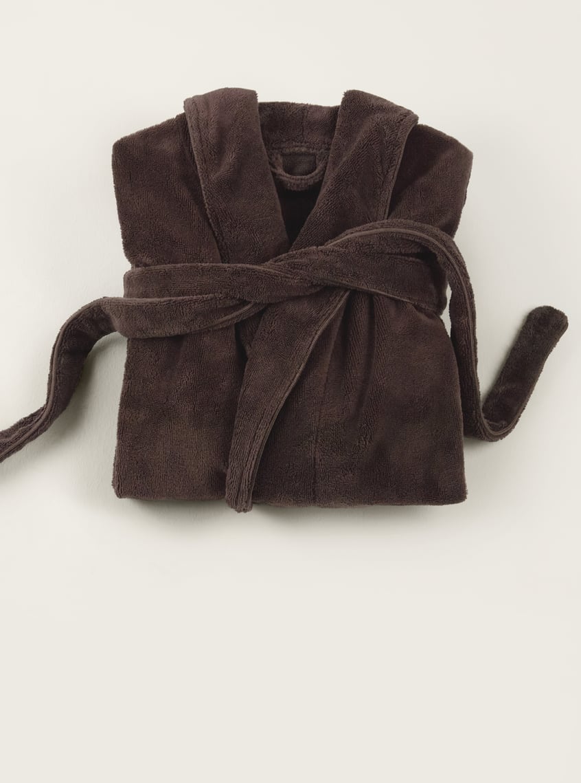 Soft bathrobe in dark brown, decoratively folded and arranged as a wellness gift idea.