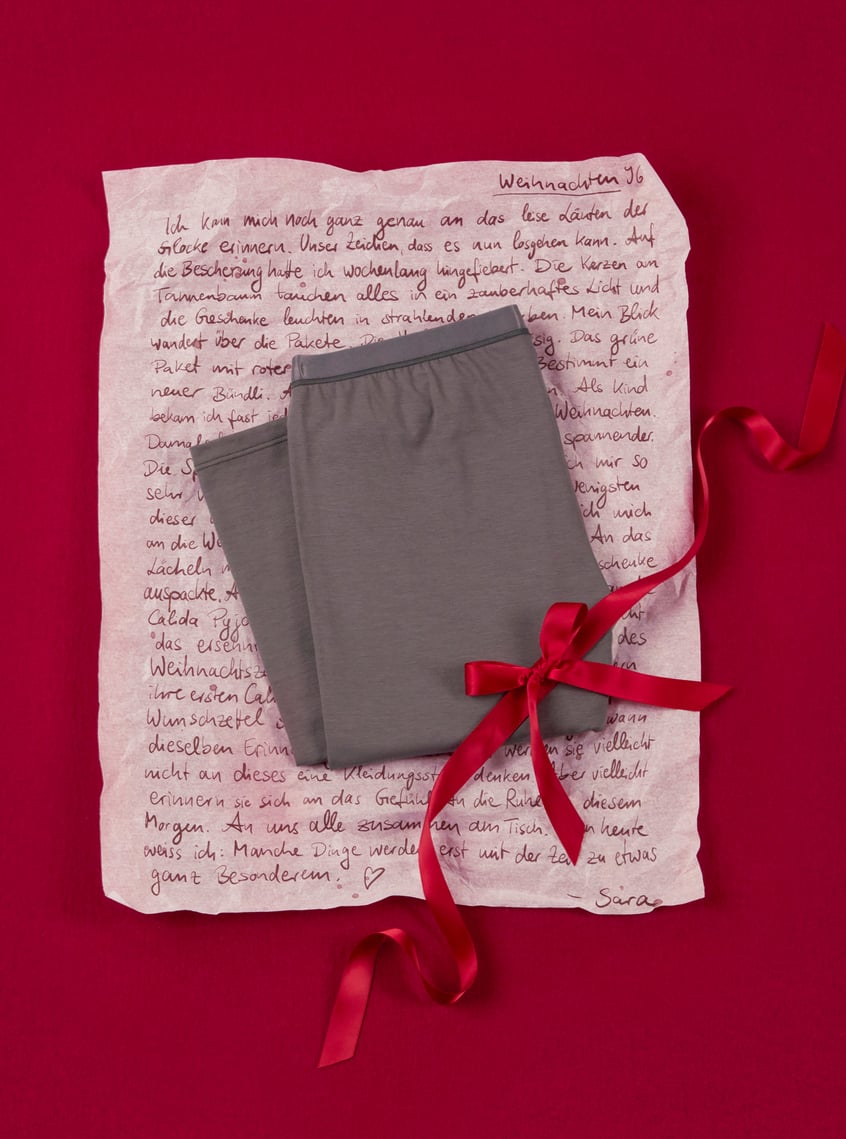 Trendy homewear pants in grey, arranged with a gift ribbon and personal touch on a festive background.