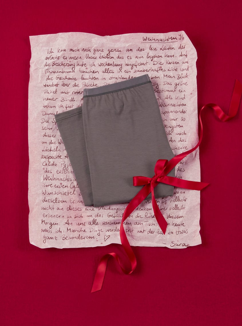 Trendy homewear pants in grey, arranged with a gift ribbon and personal touch on a festive background.